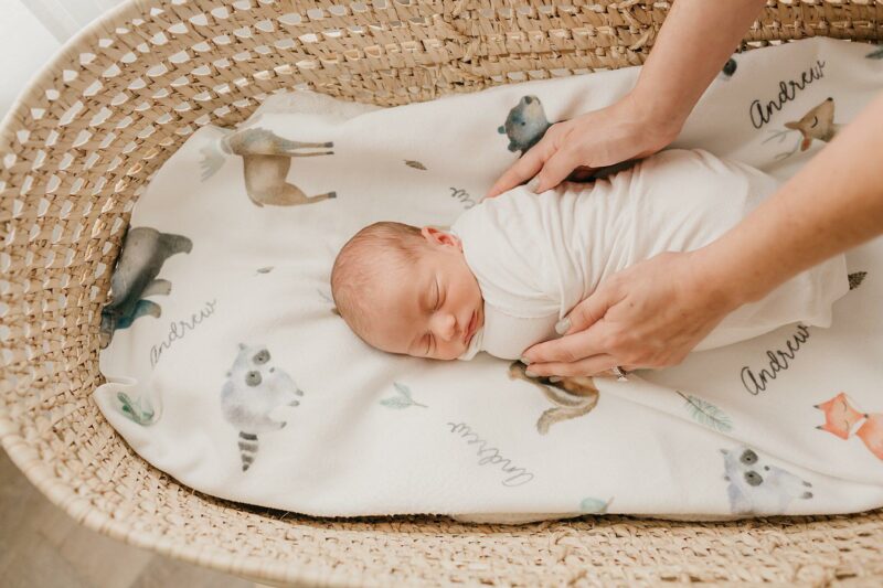 Person tucking in a sleeping newborn baby